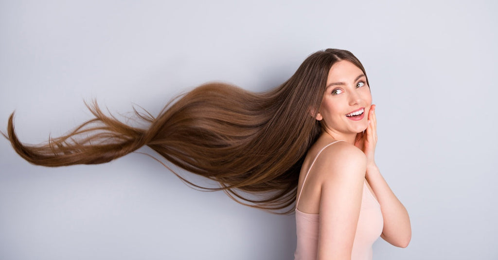 A Caucasian brunette posing with her long hair flowing in the air. She is wearing a light pink nightgown.